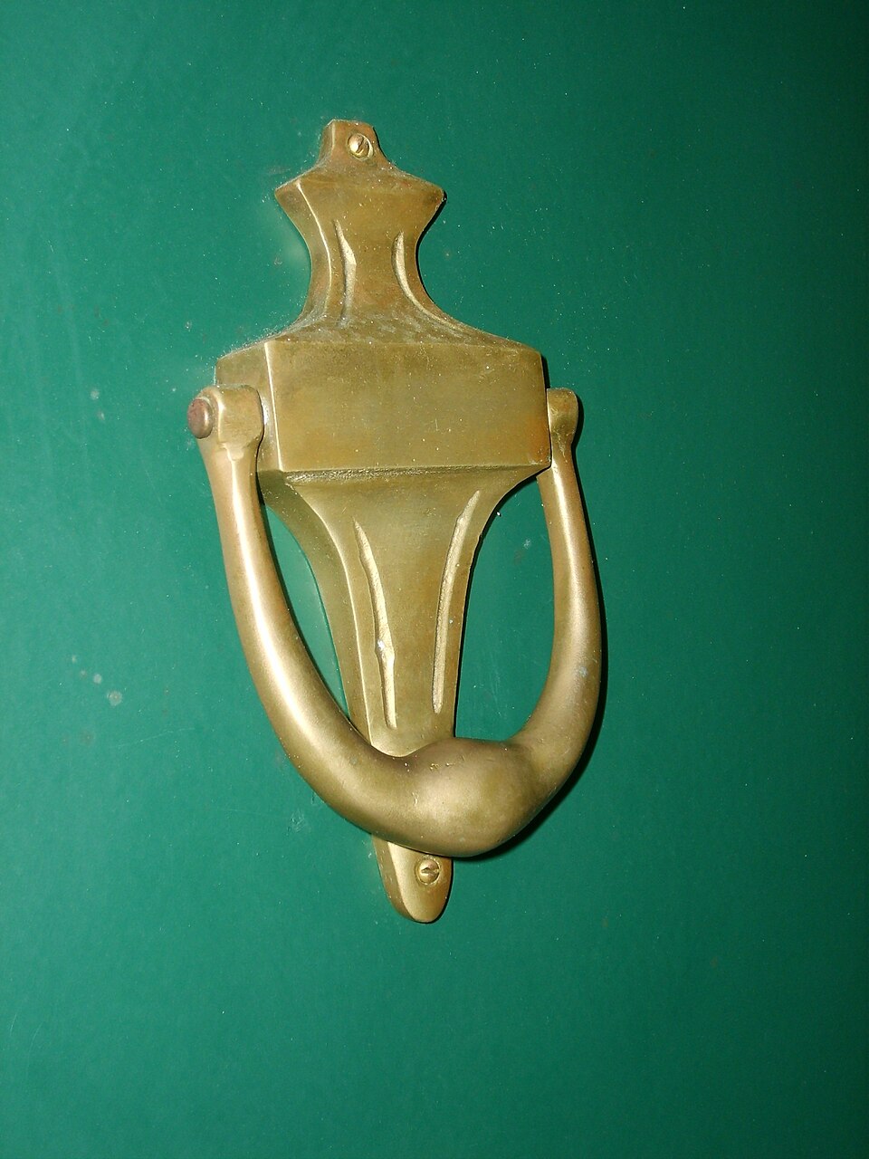 Brass urn-shaped knocker against a green painted door.