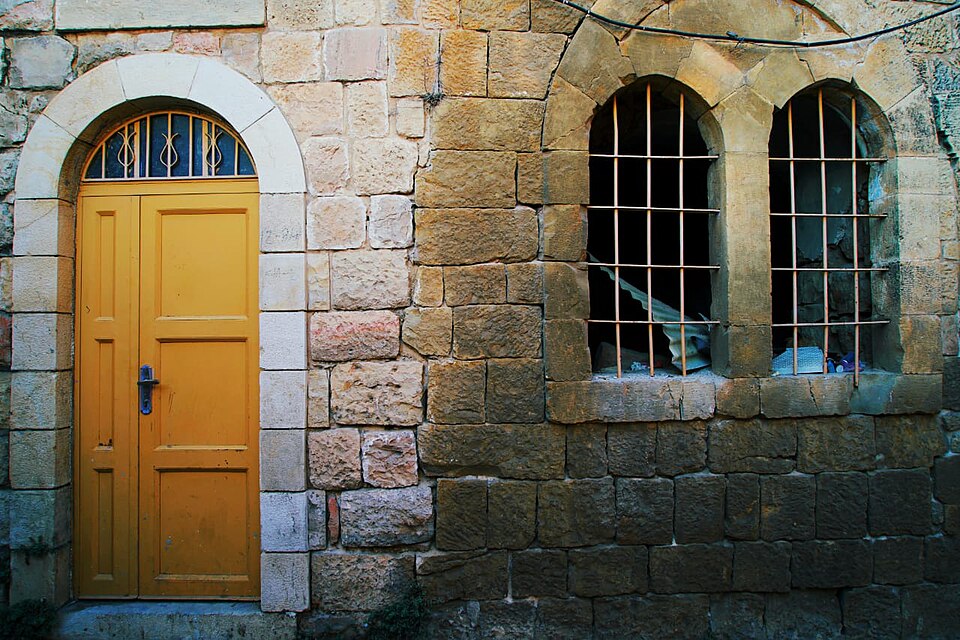 Ochre painted door in a rounded stone opening.