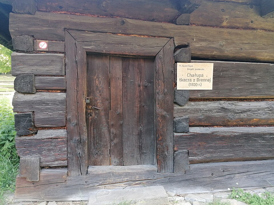 Weathered plank door in the log wall of a historic cottage.