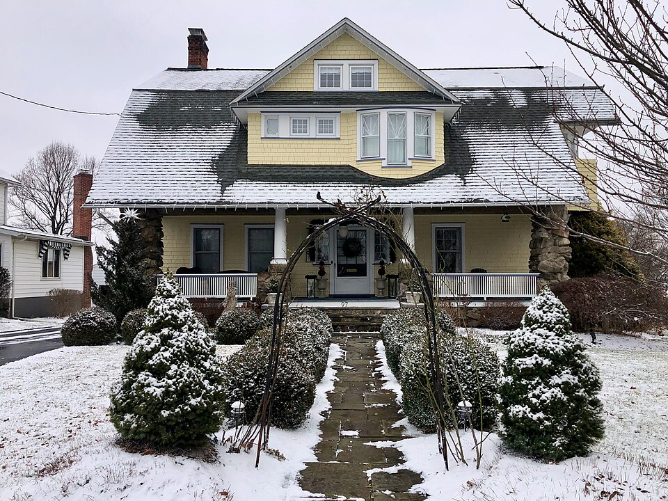 Snow-covered approach to a broad porch on a bungalow in Danbury, Connecticut.