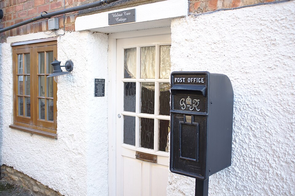 White cottage entrance with a glazed door and a wall-mounted post box.
