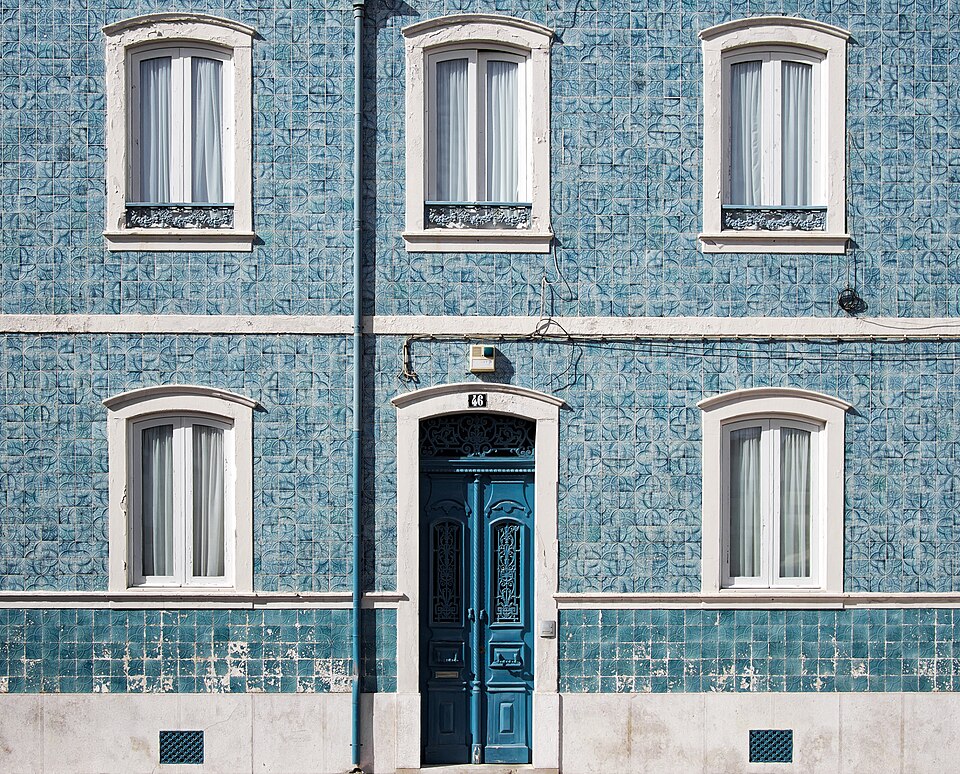 Teal entrance door in a blue tiled facade.