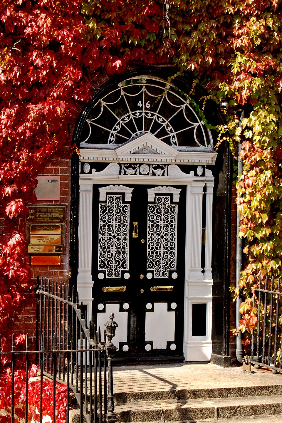 Ornamental glazed entrance surrounded by autumn foliage.