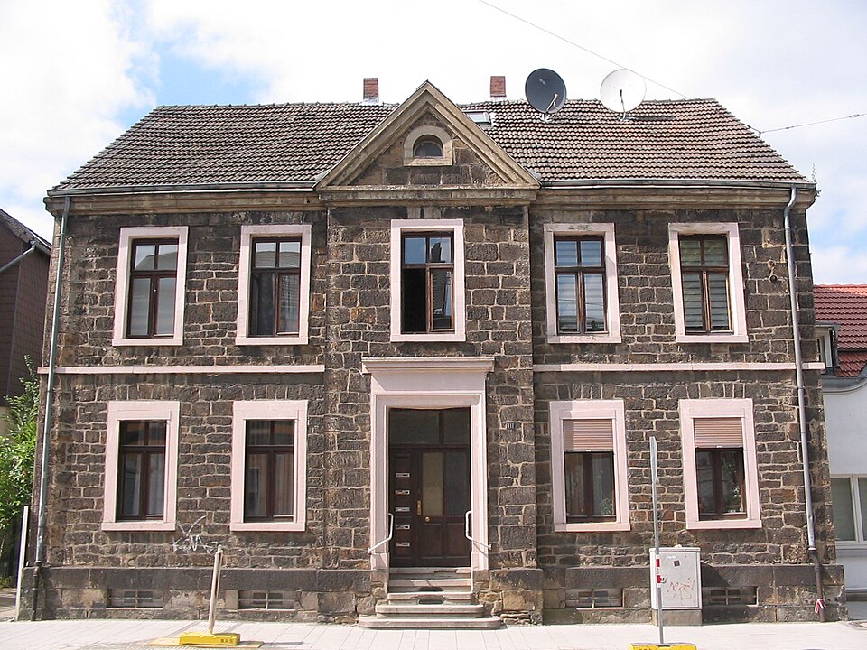Symmetrical dark house facade with a centered paneled entrance.