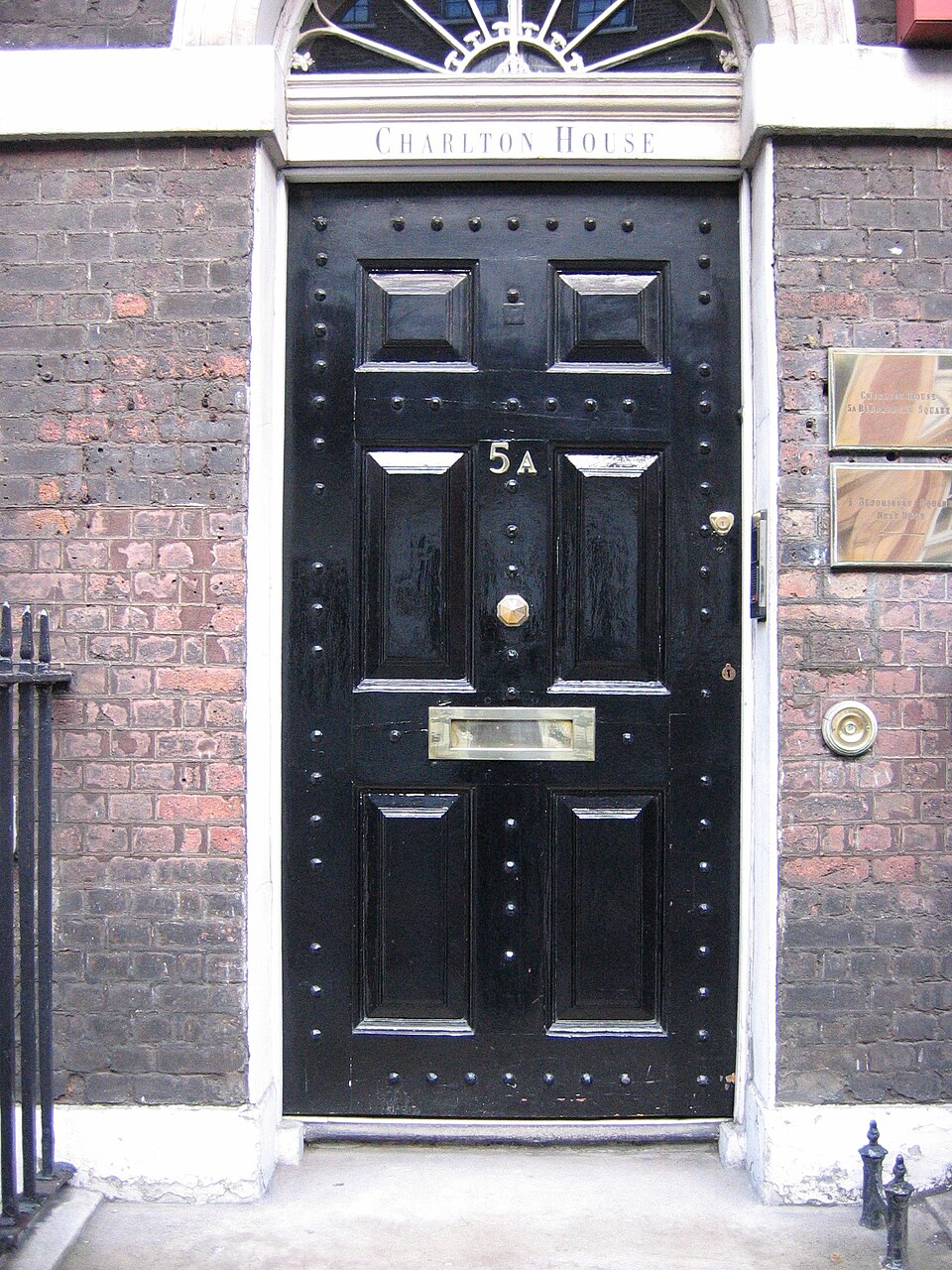 Glossy black paneled door with brass mail slot and hardware.