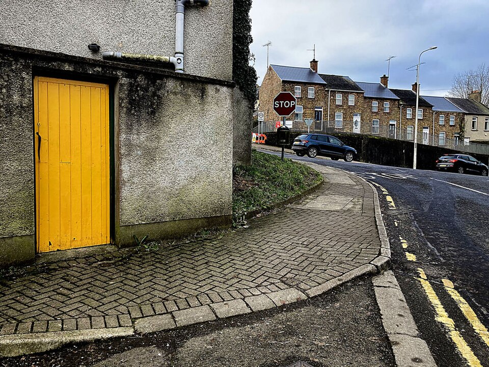 Yellow plank door opening onto a paved sloping street.