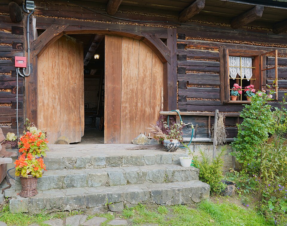 Rustic timber double entrance above stone steps with flower pots.