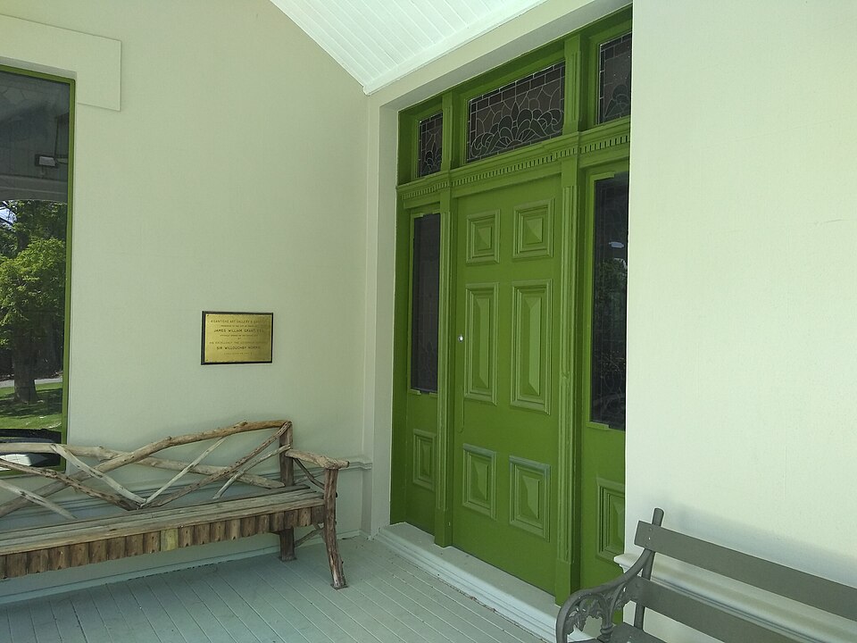 Green door and sidelights in a sheltered gallery porch.