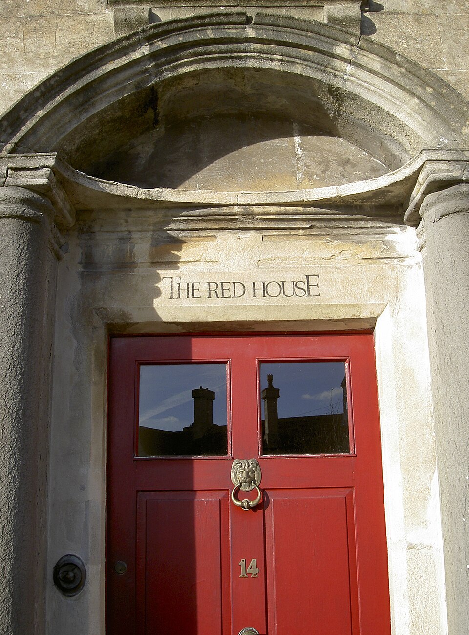 Red paneled door beneath a carved pediment and transom.