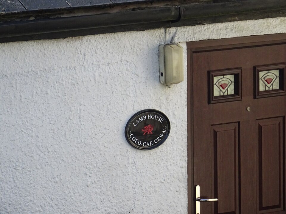 Brown paneled door with small glazed upper panes beside a house plaque.