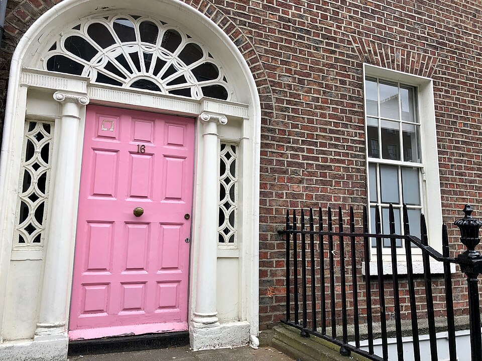 Pink paneled Dublin entrance with an ornate white fanlight surround.