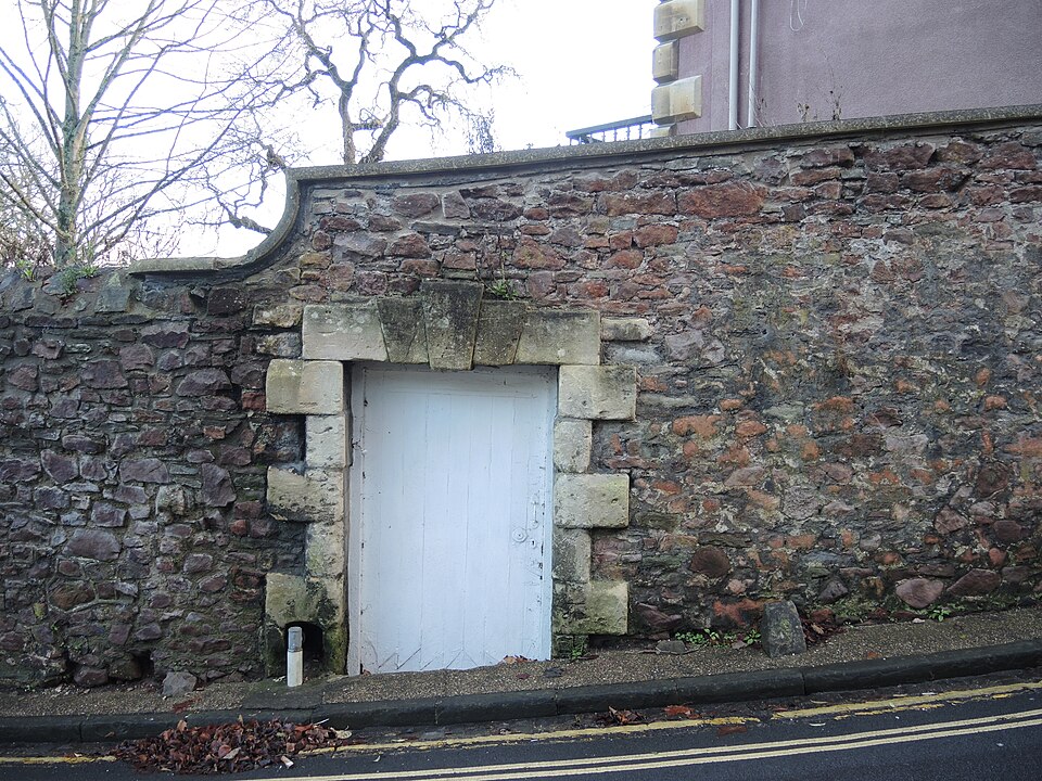 Plain pale side door set in a textured stone wall.