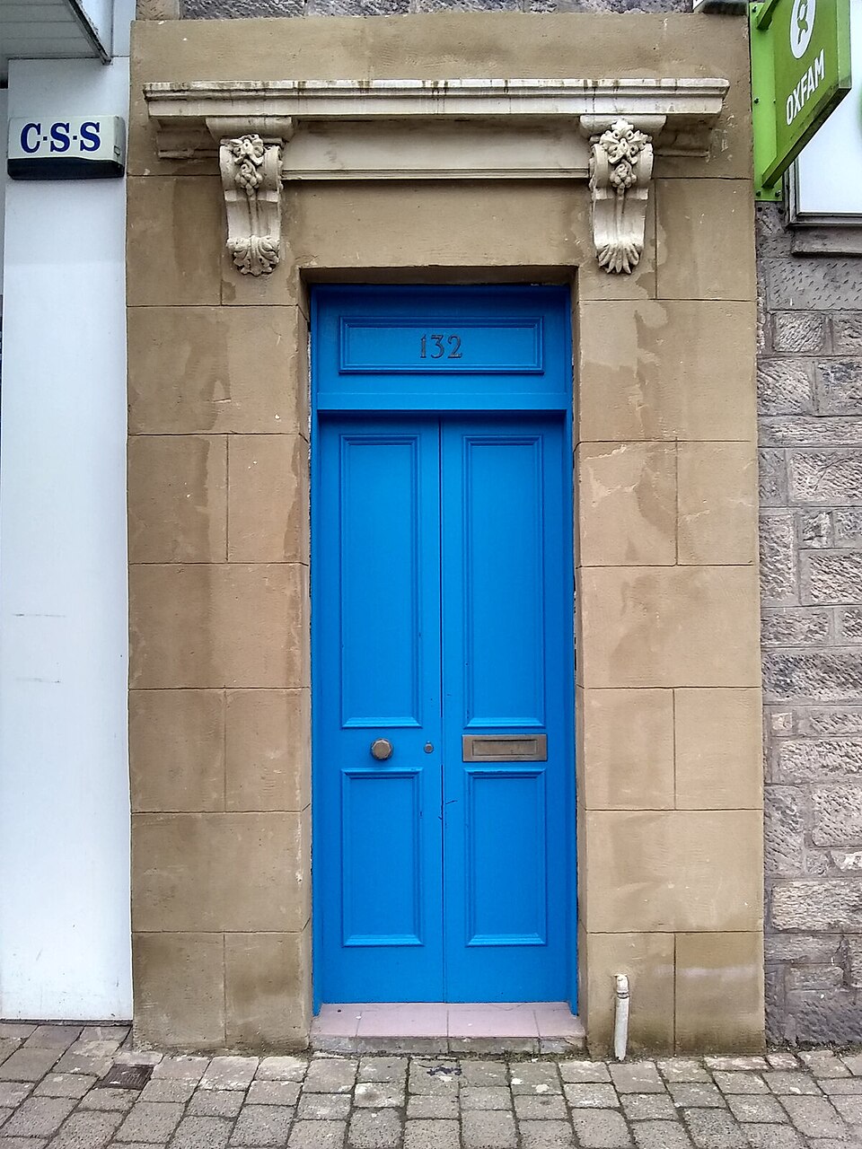 Bright blue narrow door framed by pale stonework.