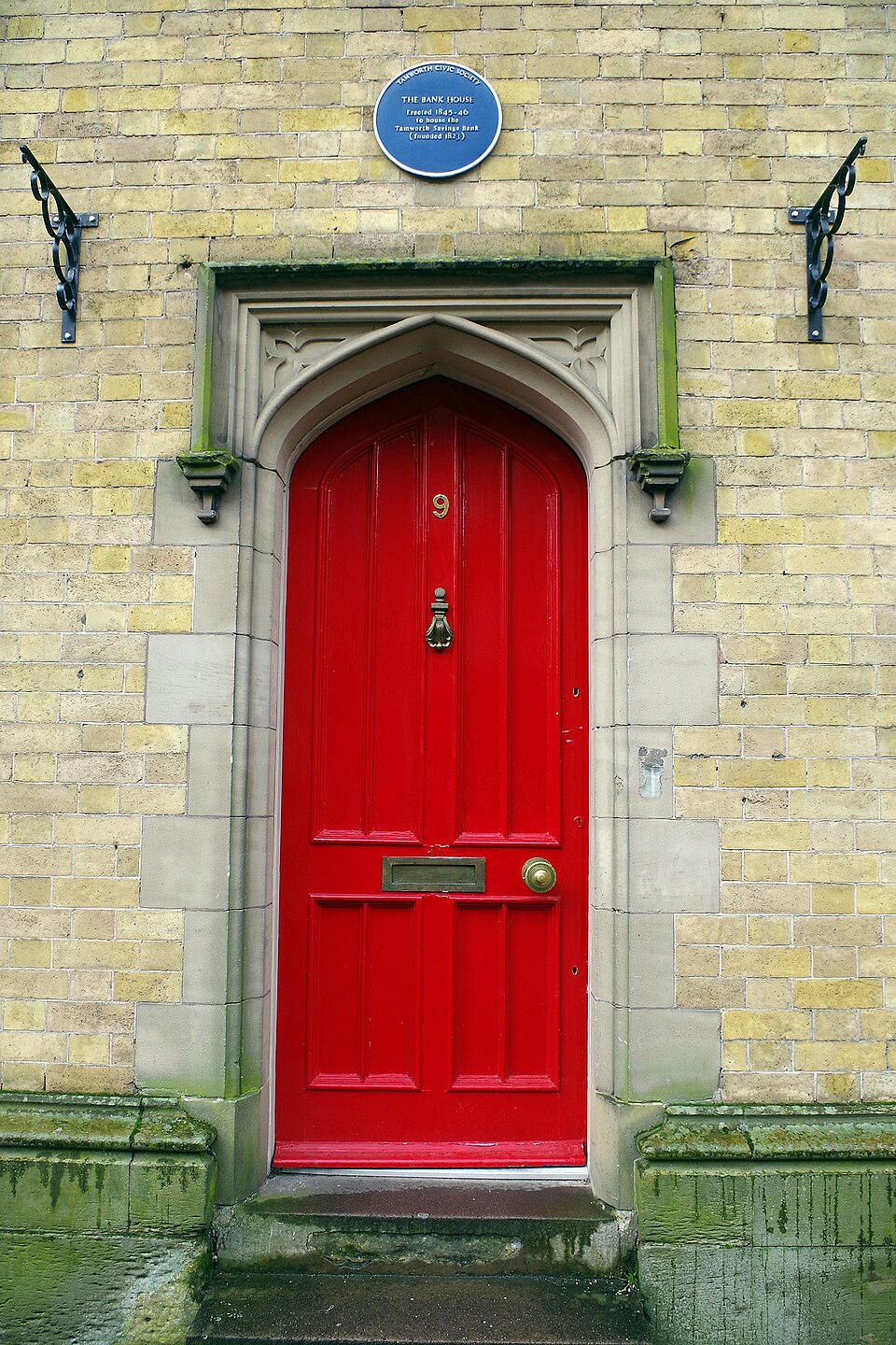 Red door under a small pointed canopy at the Old Bank House, Tamworth.