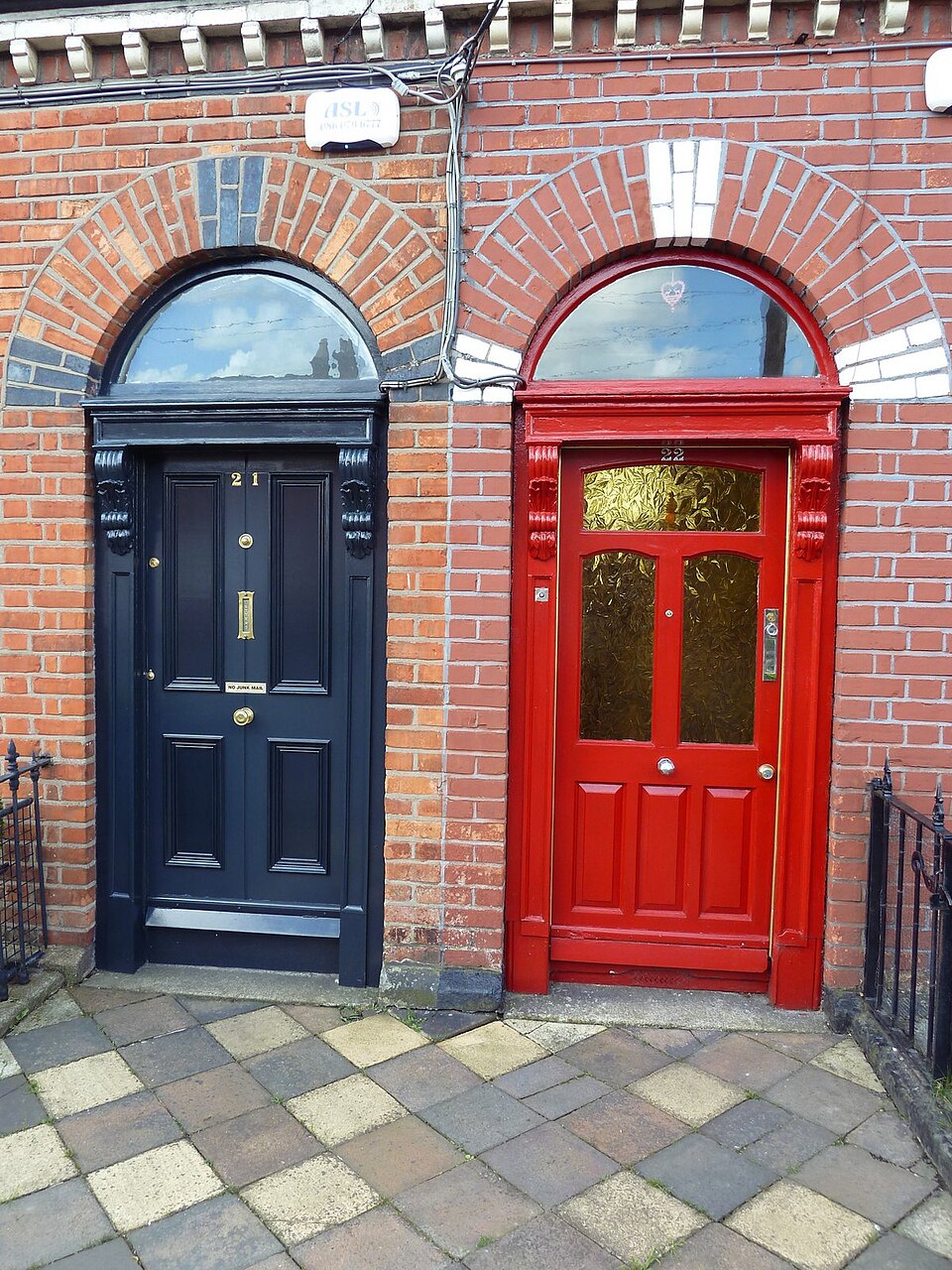 Adjacent dark blue and red Dublin entrances with arched fanlights.